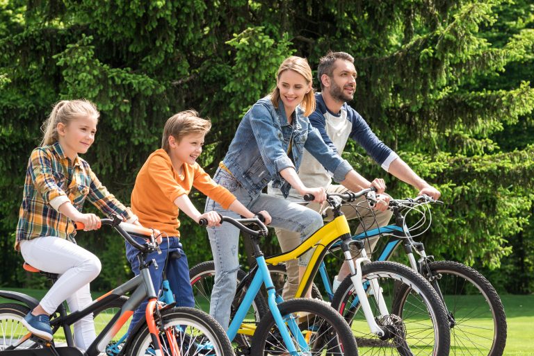 side view of happy family riding bicycles together in park